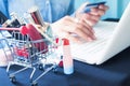Cosmetics and beauty items in shopping cart with woman using lap Royalty Free Stock Photo