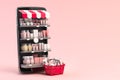 Cosmetics and beauty products buying online concept. Shopping basket with makeup products and mobile phone as shelf full of Royalty Free Stock Photo