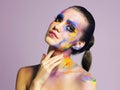 Cosmetics with character. Studio shot of an attractive young woman with brightly colored makeup against a purple