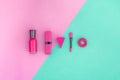 Cosmetics on colorful background. Bright pink nail polish, lipstick, eyeshadow applicator on pink and mint background