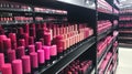 Rows of vibrant pink and red lipsticks displayed on shelves in a beauty store. Royalty Free Stock Photo
