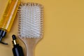 Cosmetics for hair care with jojoba, argan or coconut oil. Oil bottles and combs on orange background