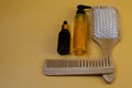 Cosmetics for hair care with jojoba, argan or coconut oil. Oil bottles and combs on orange background