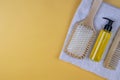 Cosmetics for hair care with jojoba, argan or coconut oil. Oil bottles and combs on a towel that stands on an orange background