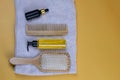 Cosmetics for hair care with jojoba, argan or coconut oil. Oil bottles and combs on a towel that stands on an orange background