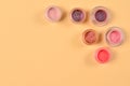 Cosmetics. Makeup. Jars with crumbly bright shadows, glitter. Pink,peach, golden colors on beige background. Closeup. Space for