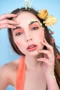 Cosmetics and manicure. Close-up portrait of attractive woman with dry flowers on her face and hair, pastel color, perfect make-up