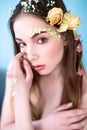 Cosmetics and manicure. Close-up portrait of attractive woman with dry flowers on her face and hair, pastel color, perfect make-up