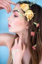 Cosmetics and manicure. Close-up portrait of attractive woman with dry flowers on her face and hair, pastel color, perfect make-up