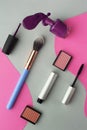 Cosmetics - mascara, blush, brush, nail polish on a pink and gray background. Beauty concept