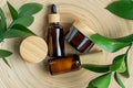 Cosmetics packaging. Set of different cosmetic bottles of cream or serum on a bamboo tray with green ruskus branches