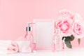 Cosmetics products for bath, spa - essential oil, bath salt, cream, liquid soap, towel, pink roses, blank frame in delicate pastel Royalty Free Stock Photo