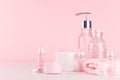 Cosmetics products for bath and spa - essential oil, bath salt, cream, liquid soap, towel in delicate pastel pink bath interior. Royalty Free Stock Photo