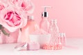 Cosmetics products for bath, spa - essential oil, bath salt, cream, liquid soap, towel and pink roses in delicate pastel pink. Royalty Free Stock Photo