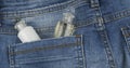 Cosmetics sticks out of the back pocket of jeans.