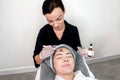 Cosmetologist administering chemical peel treatment on patient in a beauty spa, for skin rejuvenation, complexion and acne beauty