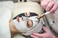 The cosmetologist applies a black and white mask on half of the face at spa salon Royalty Free Stock Photo