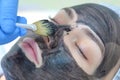 Cosmetologist applying carbon nanogel to skin of woman`s face using brush.