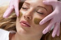 Cosmetologist applying a clay mask to the face of beautiful woman. Spa treatment and face care in the beauty salon Royalty Free Stock Photo