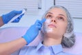 Cosmetologist is applying cream with anesthesia on patient`s face, closeup view.