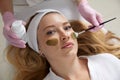 Cosmetologist applying a mask from clay to the face of a beautiful woman. Spa treatment and face care in the beauty Royalty Free Stock Photo