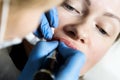 Cosmetologist applying permanent make-up. Young beautiful woman having cosmetic tattoo on her lips. Healthy Spa Royalty Free Stock Photo
