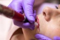 Cosmetologist applying permanent makeup on lips