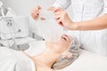 Cosmetologist applying sheet mask on woman face for rehydrate face skin, procedure in beauty salon