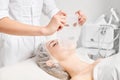 Cosmetologist applying sheet mask on woman face for rehydrate face skin, procedure in beauty salon
