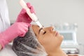 Cosmetologist, beautician in pink gloves making facial treatment with ultrasonic spatula to woman, face skin scrubber