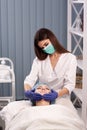 Cosmetologist in blue gloves does facial massage. Woman enjoys the procedure. Anti-aging massage. Cosmetic procedures