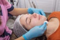 Cosmetologist cleaning face of a young woman with a cotton pads