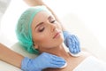 Cosmetologist cleaning face of a young woman with a cotton pads. Removing cosmetics with hygienic discs.