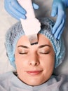 Cosmetologist cleaning woman forehead with ultrasonic scrubber.