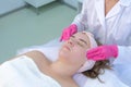 Cosmetologist cleaning woman patient`s face wiping cotton pads, closeup view.