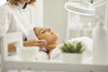 Cosmetologist cleaning womans face with cotton pads in beauty salon