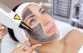 Cosmetologist does Carbon face peeling procedure of a beautiful, young woman in a beauty salon. Hardware cosmetology treatment and