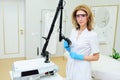 cosmetologist with glasses holds a CO2 fractional ablative laser for skin rejuvenation and scar removal in his hands and