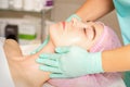 Cosmetologist with gloved hands applies a moisturizing mask with peeling cream on the female face. Facial cosmetology Royalty Free Stock Photo