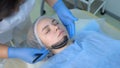 Cosmetologist applying carbon nanogel to skin of woman`s face using brush.