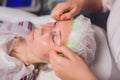 cosmetologist with the help of a special make-up brush makes a therapeutic spa mask from green algae against aging of a Royalty Free Stock Photo