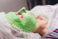 cosmetologist with the help of a special make-up brush makes a therapeutic spa mask from green algae against aging of a Royalty Free Stock Photo