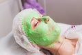 cosmetologist with the help of a special make-up brush makes a therapeutic spa mask from green algae against aging of a Royalty Free Stock Photo