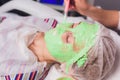 cosmetologist with the help of a special make-up brush makes a therapeutic spa mask from green algae against aging of a Royalty Free Stock Photo