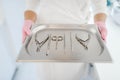 Cosmetologist holds metal tray with equipment