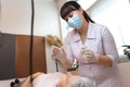 Cosmetologist holds a tube of anesthesia in one hand and with the other hand tries to apply it to the lips with a finger Royalty Free Stock Photo