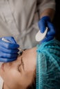 A cosmetologist injects a syringe into a patient