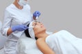 The cosmetologist makes the apparatus a procedure of Microcurrent therapy of a beautiful, young woman in a beauty salon.