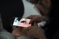 Cosmetologist makes a photo using smartphone and fixes the result of work eyelash extension procedure in a beauty salon. Self-