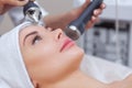 The cosmetologist makes the procedure an ultrasonic cleaning of the facial skin of a beautiful, young woman in a beauty salon Royalty Free Stock Photo